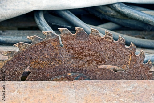 part of an old round rusty iron brown circular saw on a metal table in a workshop