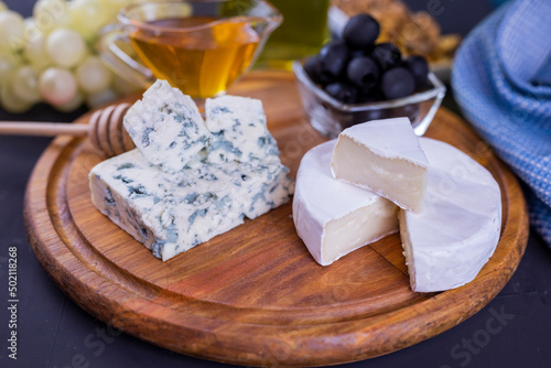 appetizer cheese dor blue and camembert on a wooden board with honey and grapes