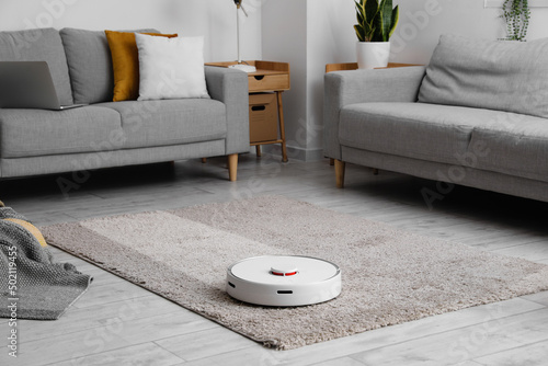 Modern robot vacuum cleaner on soft carpet in room