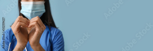 Cardiologist making heart with her hands on blue background with space for text