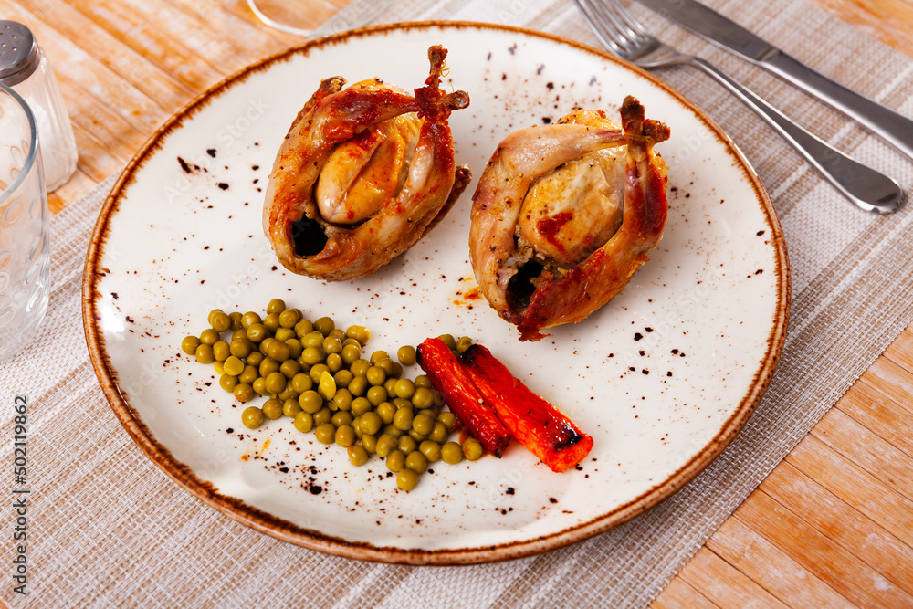 Traditional Spanish dish is two baked quails with carrots and canned