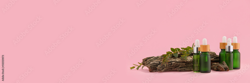 Bottles of natural cosmetic serum with herbal extract on pink background with space for text Bottles of natural cosmetic serum with herbal extract on pink background with space for text