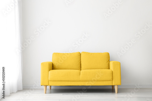 Comfortable yellow sofa near light wall