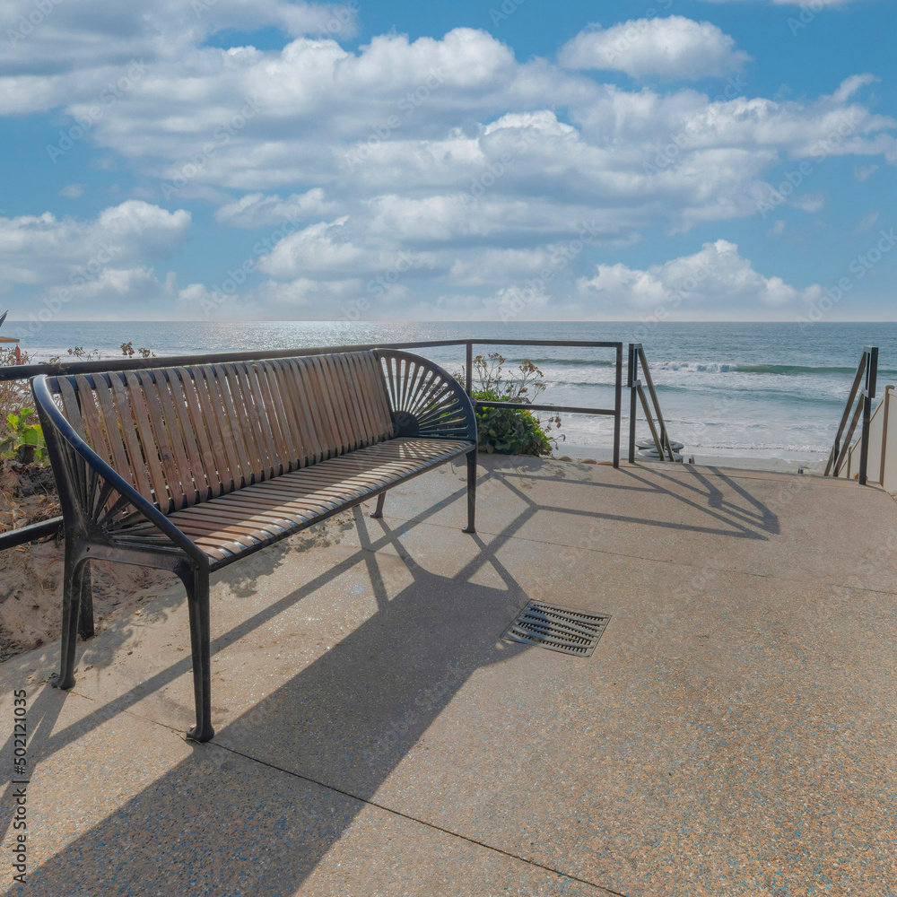 Square White puffy clouds Bench at the side of the pathway with railings and a view of the Square White puffy clouds Bench at the side of the pathway with railings and a view of the