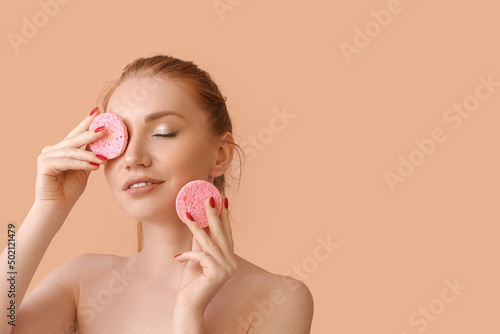 Beautiful woman with makeup sponges on color background photo