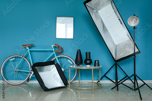 Bicycle and table with different modern equipment near color wall in photo studio interior photo