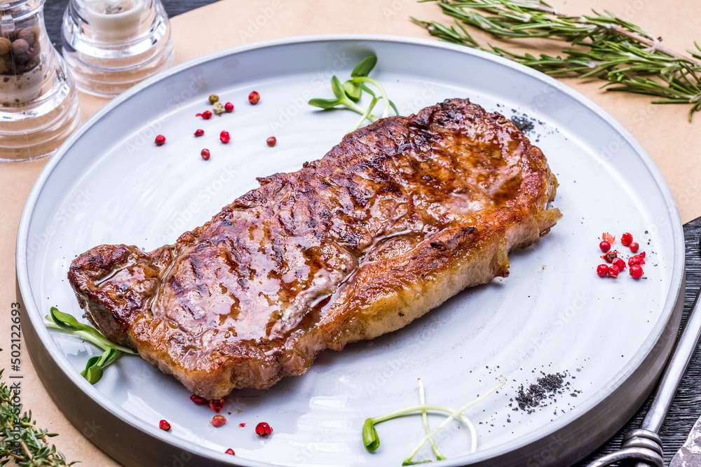juicy Striploin Steak on grey plate on table