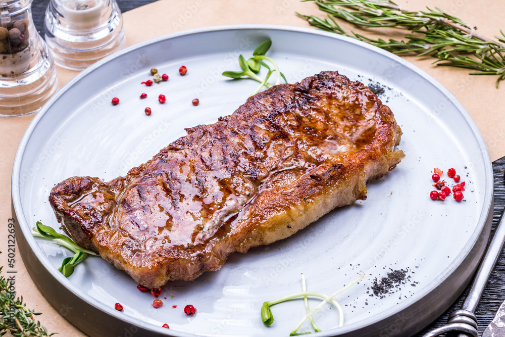 juicy Striploin Steak on grey plate on table juicy Striploin Steak on grey plate on table