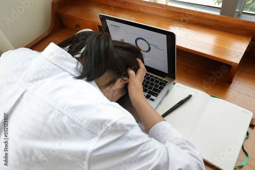 Frustrated woman lying face down on laptop at desk