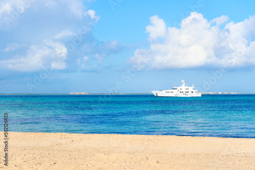 yacht on the north beach of islas mujeres with a turquoise blue ocean and the city of cancun in the background.