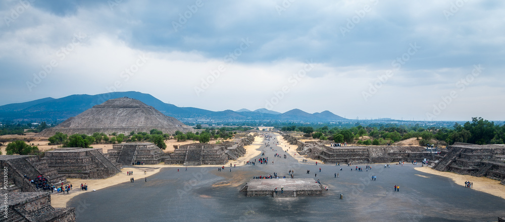 Tourists visit the ruins of the ancient city of Teotihuacán. Perspective view of the Avenue of the Dead from the Pyramid of the Moon summit with the Pyramid of the Sun in the background.