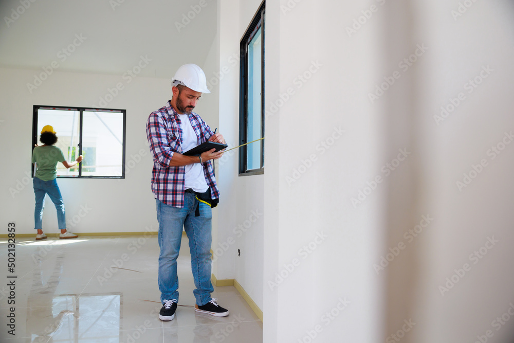 Man installing windows in new house construction site. Hispanic Construction worker wearing protect gloves and hardhat helmet Man installing windows in new house construction site. Hispanic Construction worker wearing protect gloves and hardhat helmet