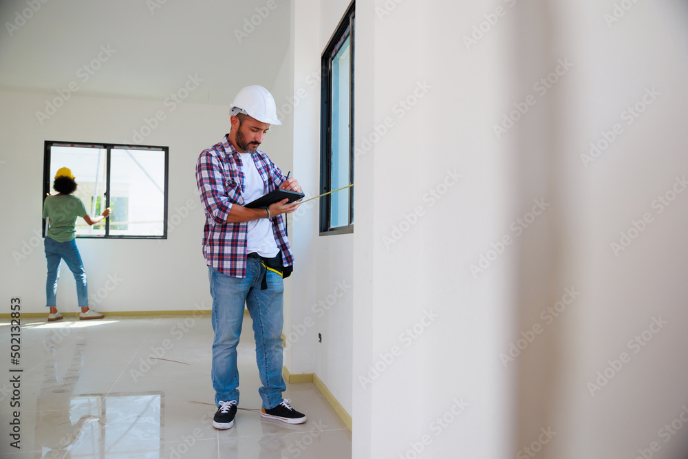 Man installing windows in  new house construction site. Hispanic Construction worker wearing protect gloves and hardhat helmet