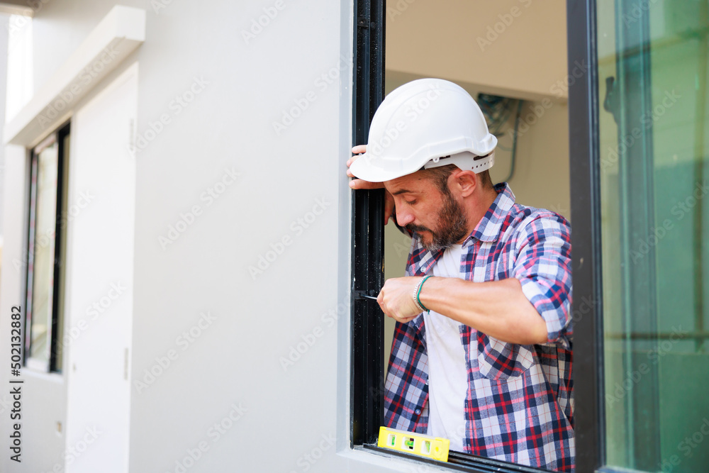 Man installing windows in new house construction site. Hispanic Construction worker wearing protect gloves and hardhat helmet Man installing windows in new house construction site. Hispanic Construction worker wearing protect gloves and hardhat helmet