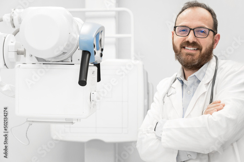 Smiling confident radiologist standing near x-ray equipment. High quality photo