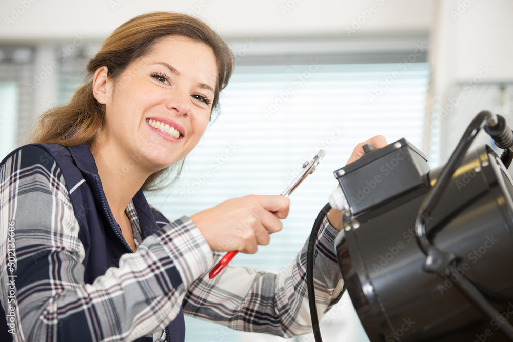 female electrician posing while working on appliance