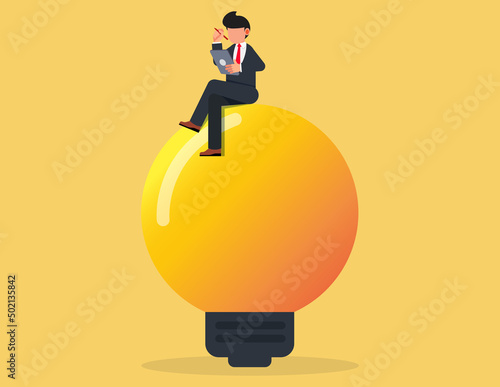 Businessman sitting on a light bulb while working.Idea, innovation, solution concept.