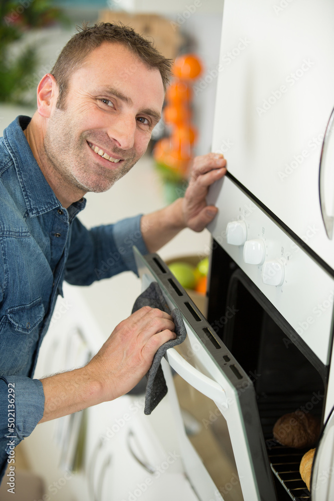 man checking food in the oven man checking food in the oven