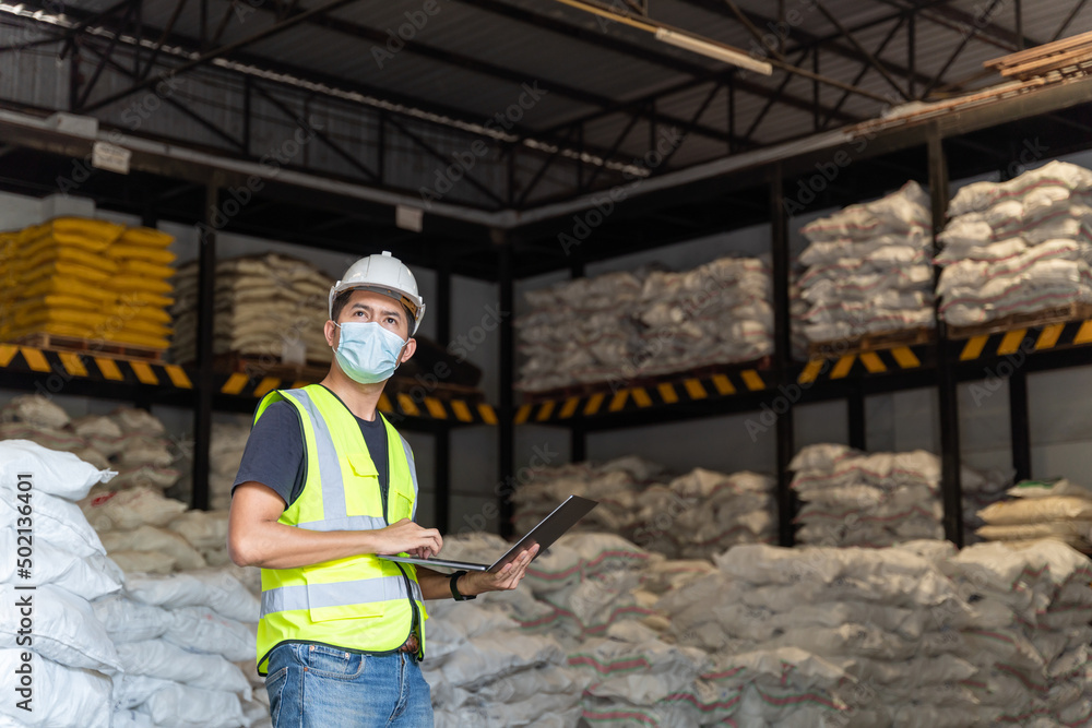 A male warehouse worker portrait with laptop in alum or chemical warehouse storage. International export business concept. A male warehouse worker portrait with laptop in alum or chemical warehouse storage. International export business concept.