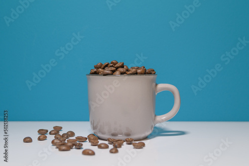 Gray cup with coffee beans on a blue background. copy space