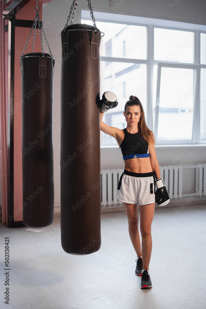 Photo shoot for a young athlete in the interior of a boxing gym with gloves and bags