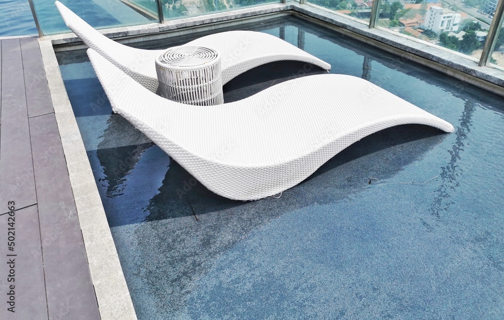 Obraz premium Softseats on the edge of the pool with Waves on the water surface The water ripples in the pool and overlooking blurred bright blue ceramic tiles that cover the floor of the pool with selective focus 