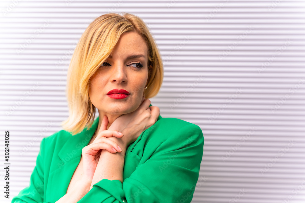 Portrait of a beautiful blonde model in a green jacket on a gray background in the city, in a fashion pose Portrait of a beautiful blonde model in a green jacket on a gray background in the city, in a fashion pose