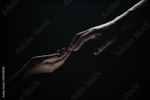 Hands gesturing on black background. Giving a helping hand. Support and help, salvation. Hands of two people at the time of rescue. Romantic touch with fingers, love. Hand creation of adam. © Volodymyr