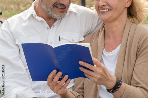 Senior couple smiling and laughing while reading a book together. retired parent activity. man and woman spending time on weeknd photo