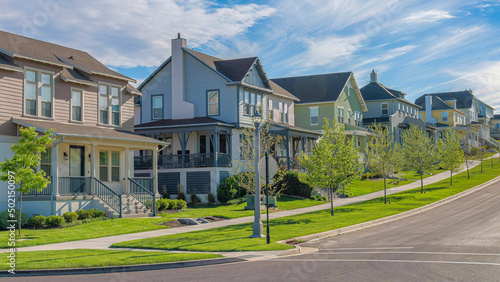 Fotografía Panorama Whispy white clouds Row of large two-storey houses near the paved uphil