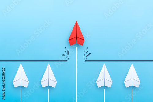 Red paper plane breaking through obstacle on blue background, Concept of overcoming barriers, goal, target photo