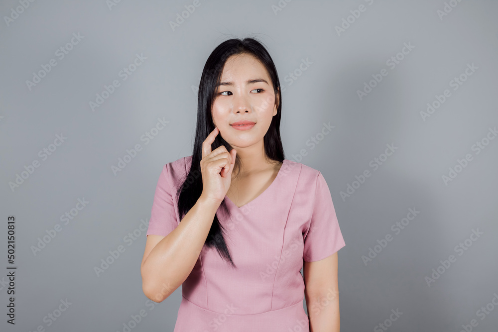 Beautiful asian woman on gray background, holding hand near the face Beautiful asian woman on gray background, holding hand near the face