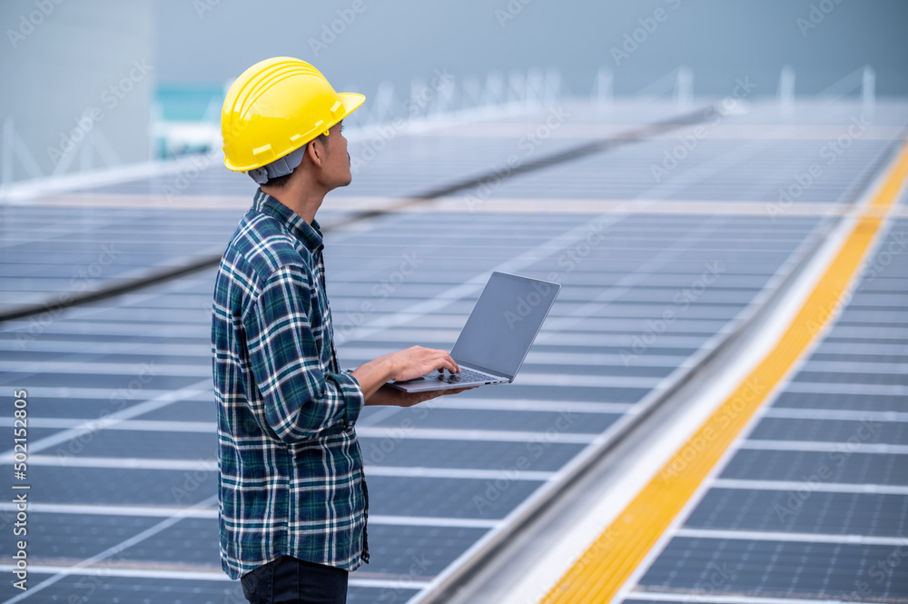 Asian engineer using computer working in solar power plant rooftop for control power system eco environmental Asian engineer using computer working in solar power plant rooftop for control power system eco environmental