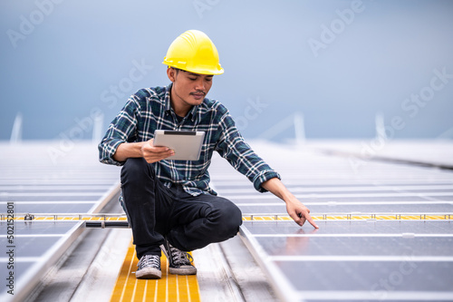 Asian engineer using tablet checking in solar power system for industrial ecology control top roof factory