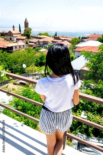 Young caucasian woman overlooks panoramic view of Sighnaghi historical buildings background