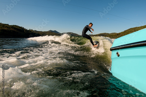 great view on active man on a wakesurf skillfully riding on a splashing wave