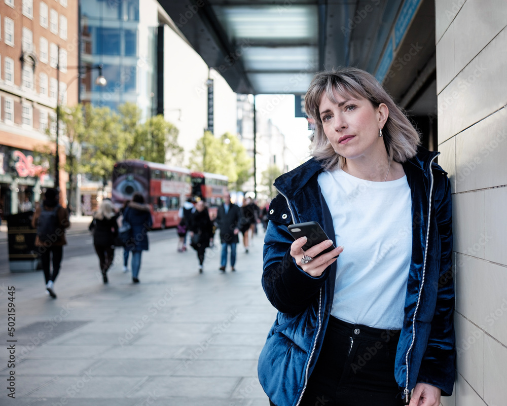 Fototapeta premium Mature woman with a mobile waiting at station door.