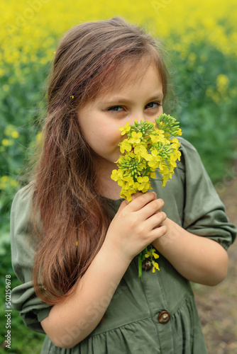 a cute six-year-old girl holds a bouquet of rapeseed flowers 