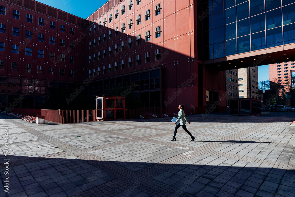 © Westend61 - Businesswoman with laptop walking in office campus © Westend61 - Businesswoman with laptop walking in office campus