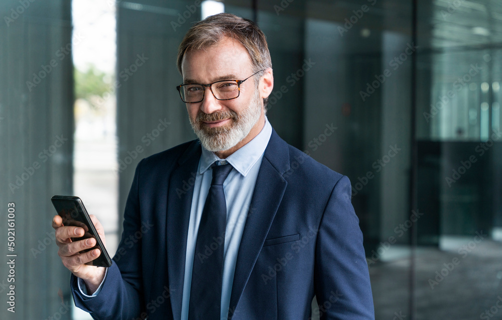 Smiling businessman holding smart phone Smiling businessman holding smart phone