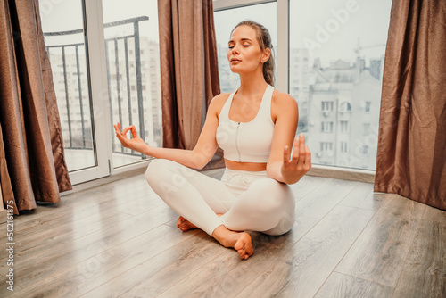 Young woman meditating at home. Girl practicing yoga in class. Relaxation at home, body care, balance, healthy lifestyle, meditation, mindfulness, recreation, workout, fitness, training concept