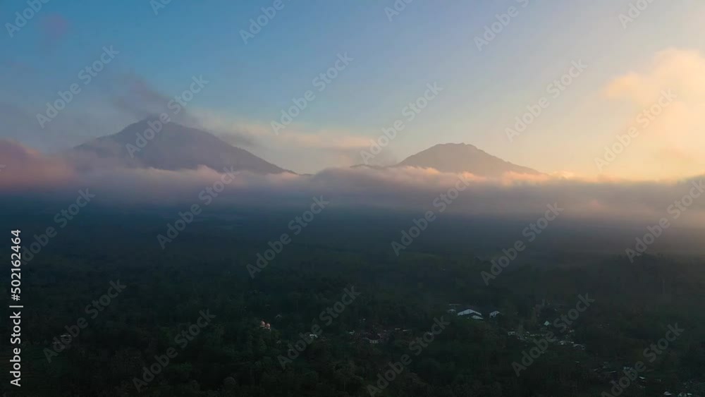 Dramatic aerial view of 2 volcanoes of a beautiful mountain range surrounded by clouds during sunrise on the background. Ijen volcano complex is a group of composite volcanoes in East Java, Indonesia Dramatic aerial view of 2 volcanoes of a beautiful mountain range surrounded by clouds during sunrise on the background. Ijen volcano complex is a group of composite volcanoes in East Java, Indonesia