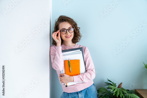 Smiling woman adjusting eyeglasses leaning on wall photo
