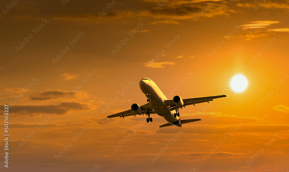 Passenger commercial aircraft flying under the clouds in sunset light. Passenger commercial aircraft flying under the clouds in sunset light.