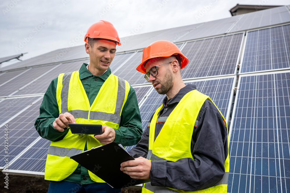 two young men in special helmets make notes after inspecting the solar panels. two young men in special helmets make notes after inspecting the solar panels.