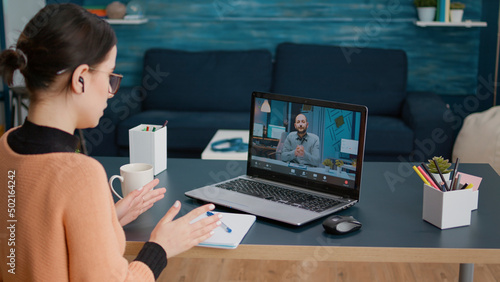 Young woman meeting with teacher on remote video call, talking about online class education and lesson. Student chatting with man on videoconference webinar, using laptop with webcam. photo