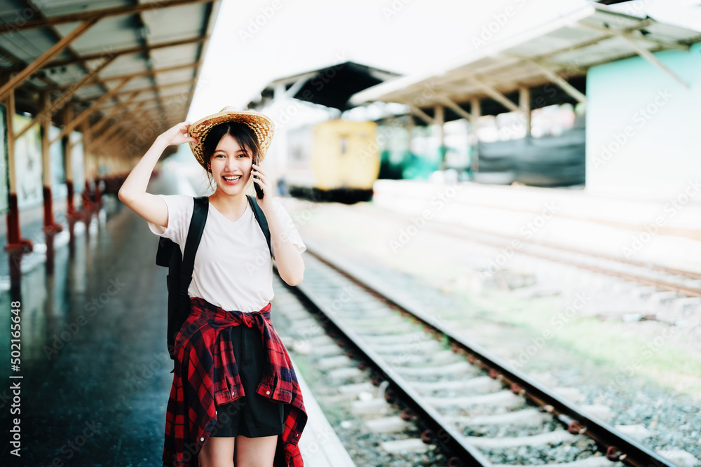 summer, relax, vacation, travel, portrait of beautiful Asian girl using the smartphone mobile to call friends at the train station while waiting for their travel time.