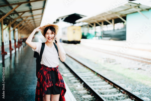 summer, relax, vacation, travel, portrait of beautiful Asian girl using the smartphone mobile to call friends at the train station while waiting for their travel time. © Jirapong