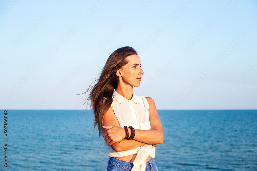 Beautiful young woman in denim shorts and shirt at the sea. Beautiful young woman in denim shorts and shirt at the sea.