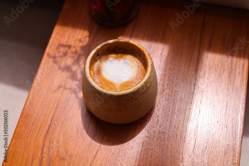 Coffee cup with latte art on the wood table.